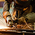 photograph of a machinist working on a piece of metal with a grinding tool as sparks fly