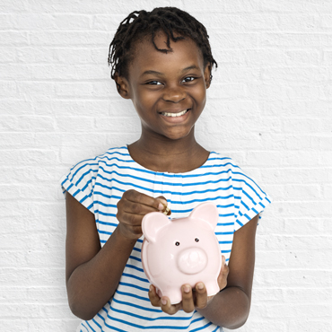 girl putting coin in piggy bank